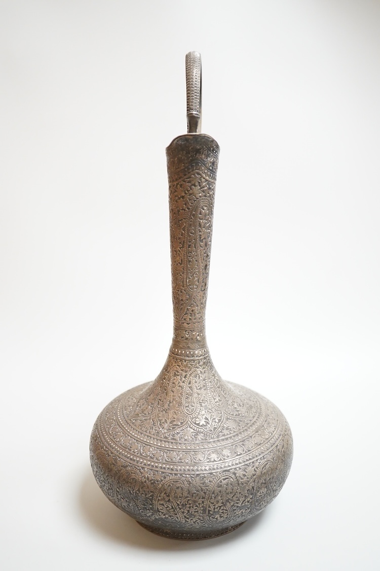 A late 19th century Indian white metal ewer, with extensive foliate decoration and cobra handle, height 30.3cm.